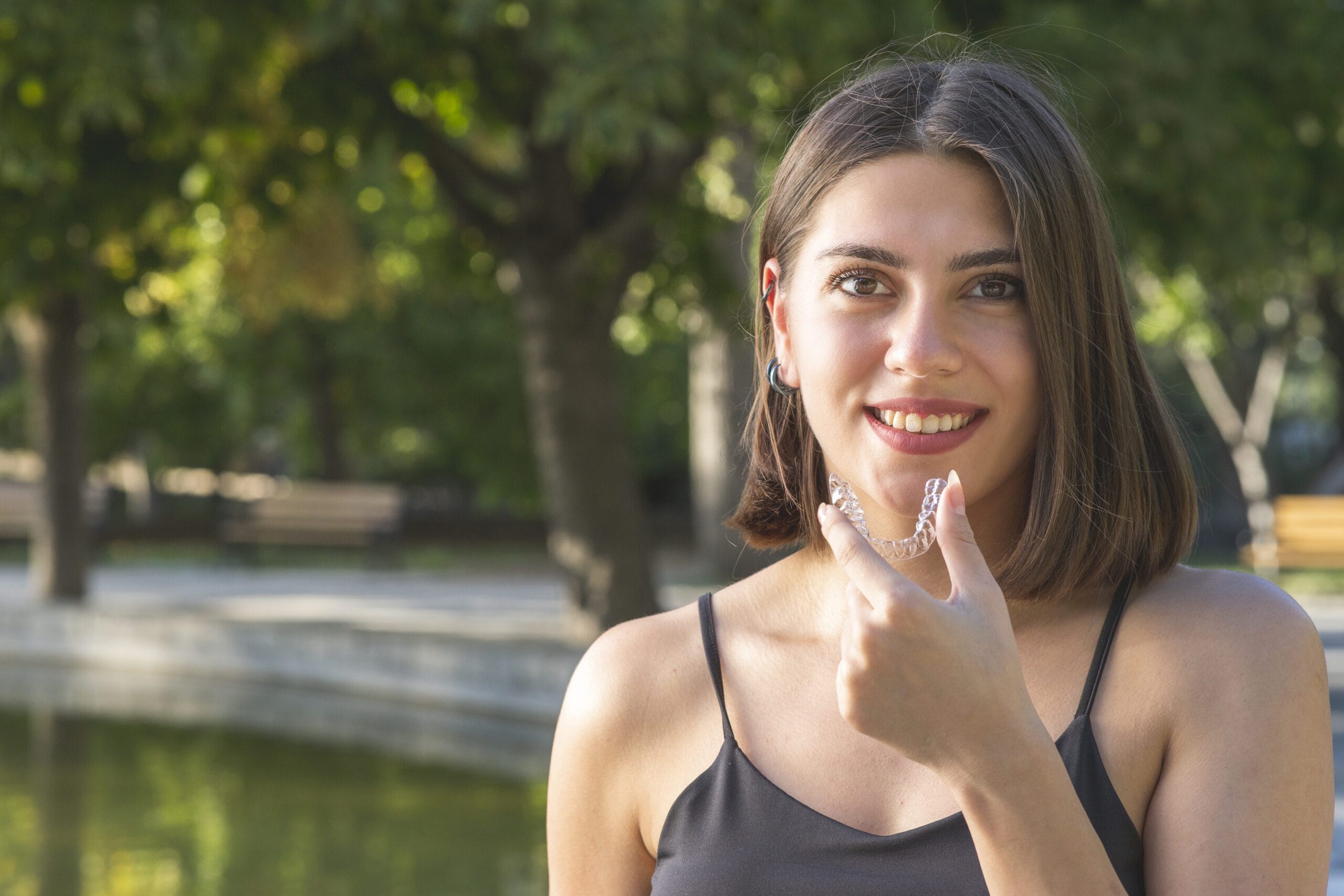 young woman with invisaligne in hands while smile with a beautiful tooth